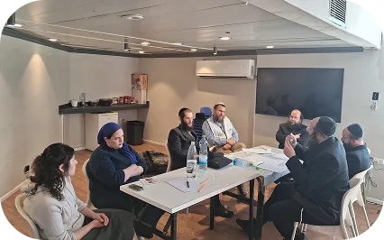 צוות ארגון יד אחת בישיבת עבודה סביב שולחן בחדר הדרכה